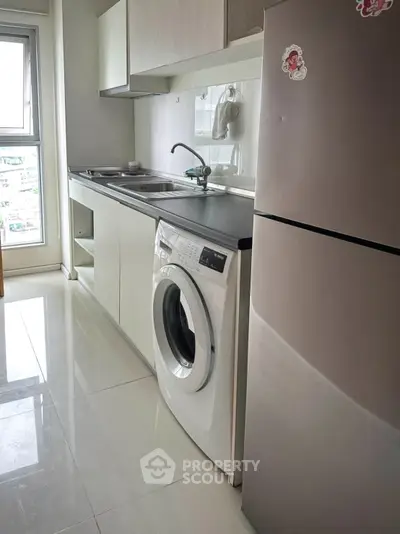 Modern kitchen with sleek appliances and washing machine in a compact layout.