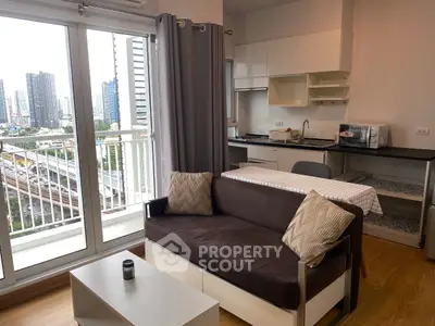 Modern apartment living room with balcony and city view, featuring a cozy sofa and compact kitchen area.