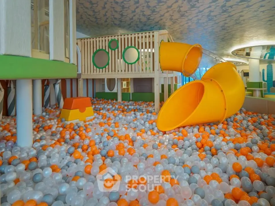 Vibrant indoor play area with colorful ball pit and slide in modern residential complex.