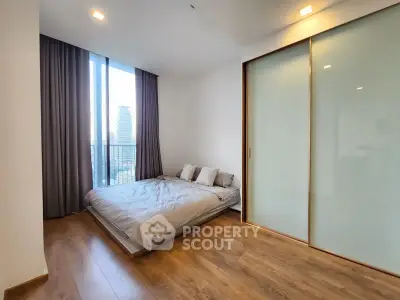 Modern bedroom with large window and wooden flooring in urban apartment