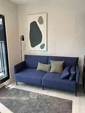 Modern living room with stylish blue sofa and abstract art, perfect for urban living.