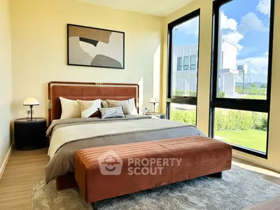 Luxurious bedroom with large windows and modern decor, offering a serene view and abundant natural light.