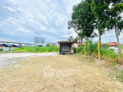 Spacious vacant land with potential for development, featuring lush greenery and clear skies.