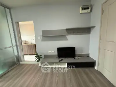 Modern living room with sleek TV stand and open kitchen view, featuring stylish shelving and wood flooring.