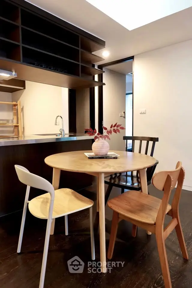 Chic dining area with modern wooden table and chairs, open kitchen layout, and stylish decor.