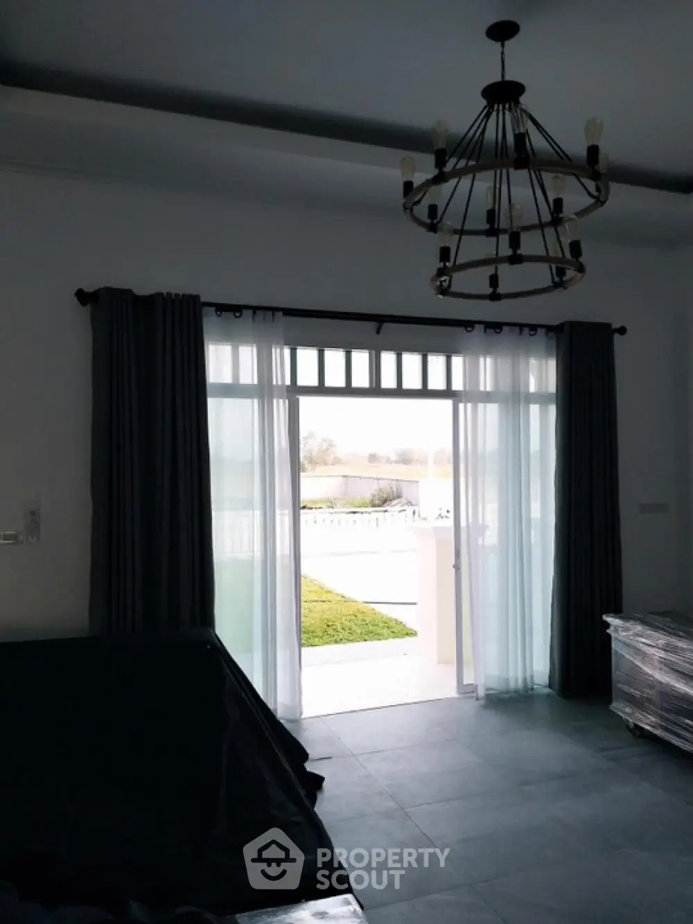 Spacious living room with elegant chandelier, large windows, and direct garden access, offering a blend of comfort and luxury for sophisticated living.