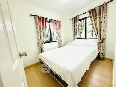 Bright and cozy bedroom with large windows and elegant curtains, perfect for relaxation.