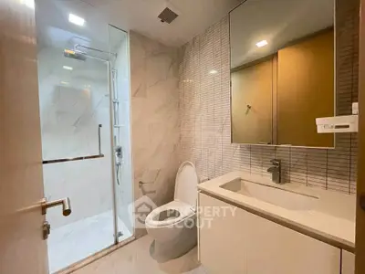 Modern bathroom with sleek design, featuring a glass shower and elegant fixtures.