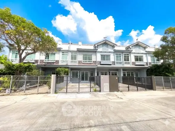 Charming townhouse exterior with modern design and lush greenery under a bright blue sky.