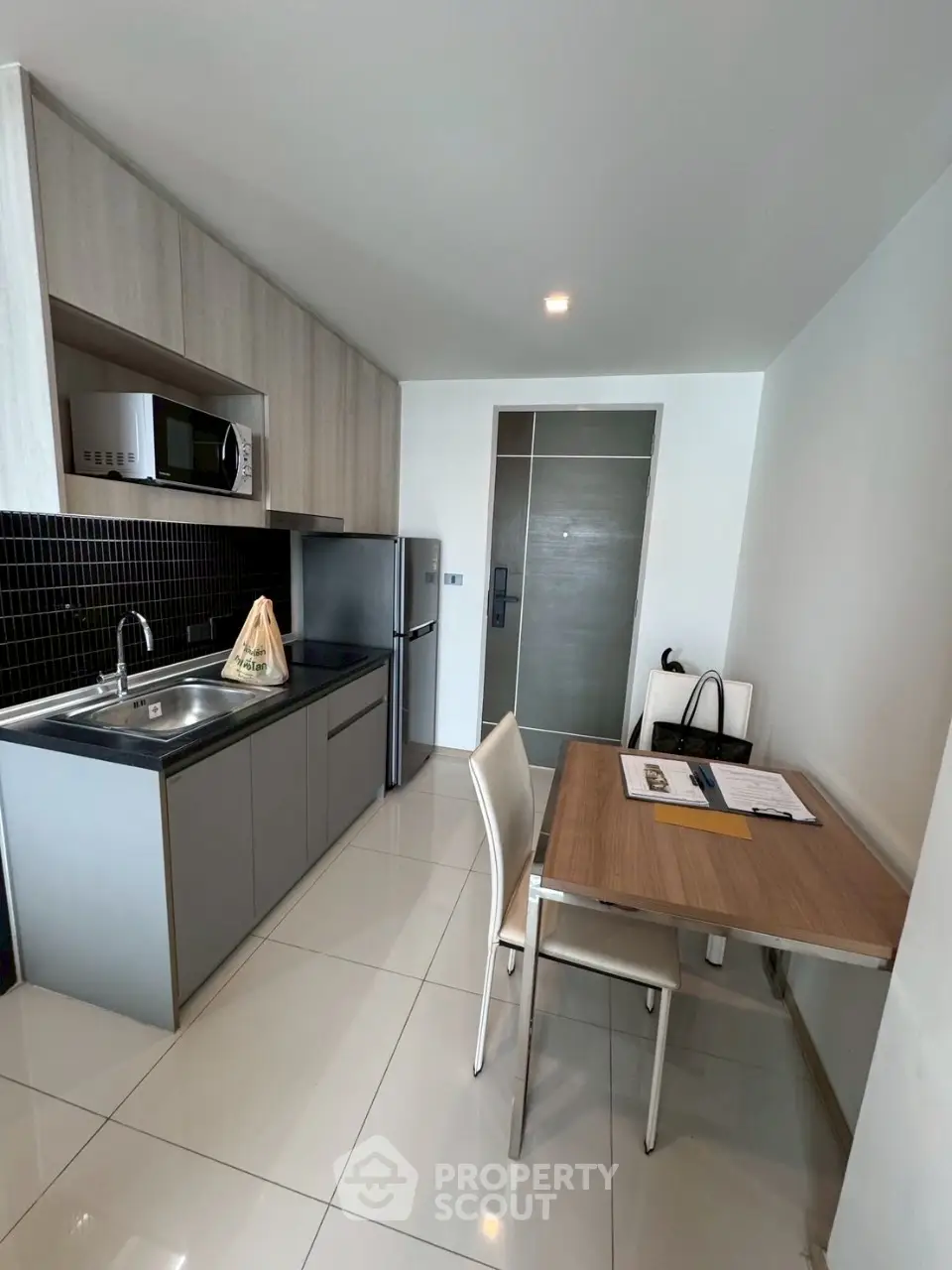 Modern kitchen with sleek cabinetry, dining area, and stainless steel appliances in a compact layout.
