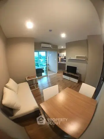 Modern living room with open layout and wooden flooring, featuring a cozy sofa and dining area.
