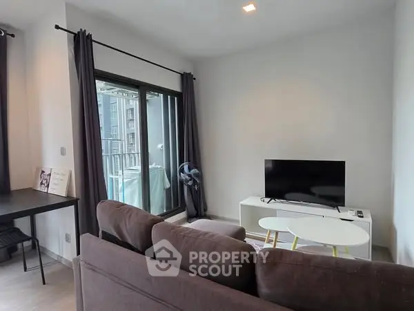 Modern living room with cozy sofa, TV, and balcony view in a stylish apartment.