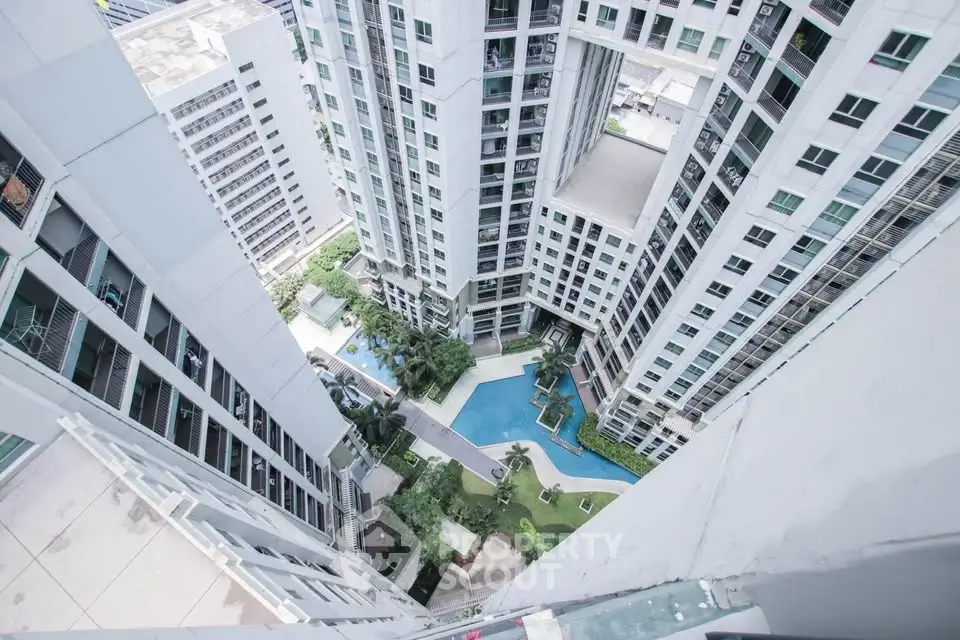 Stunning aerial view of modern high-rise residential complex with pool and lush greenery.