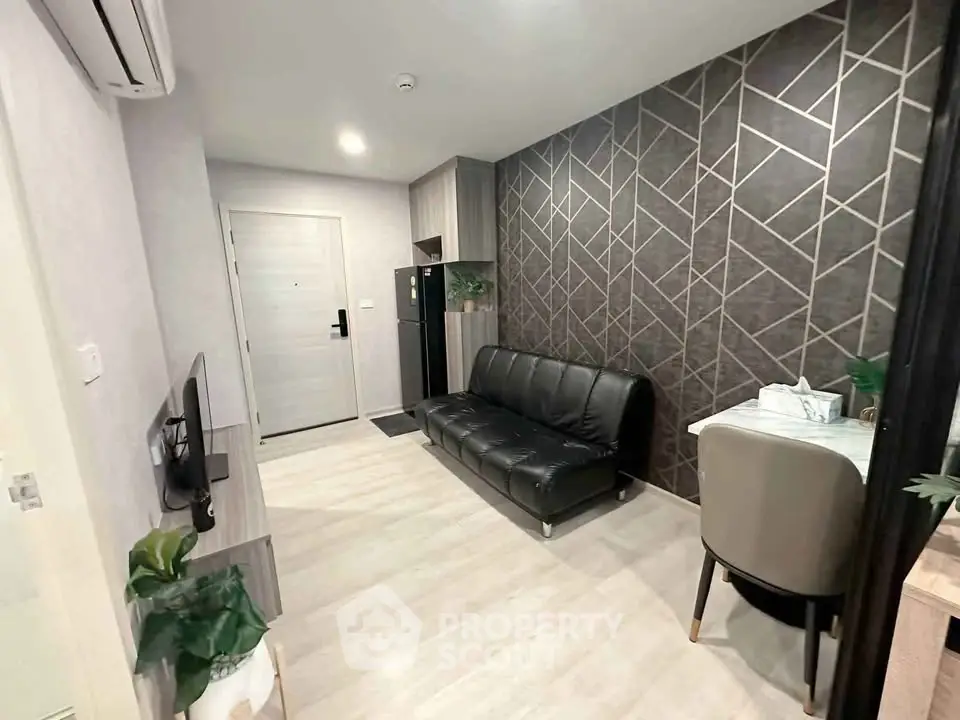 Modern living room with geometric accent wall and sleek black sofa in stylish apartment.