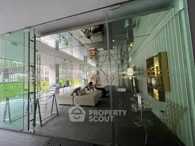 Modern glass-walled living area with stylish decor and outdoor view