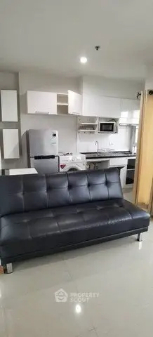 Modern apartment interior with sleek black sofa and contemporary kitchen appliances.