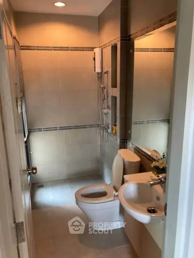 Modern bathroom with sleek fixtures and neutral tiles, featuring a shower and toilet.