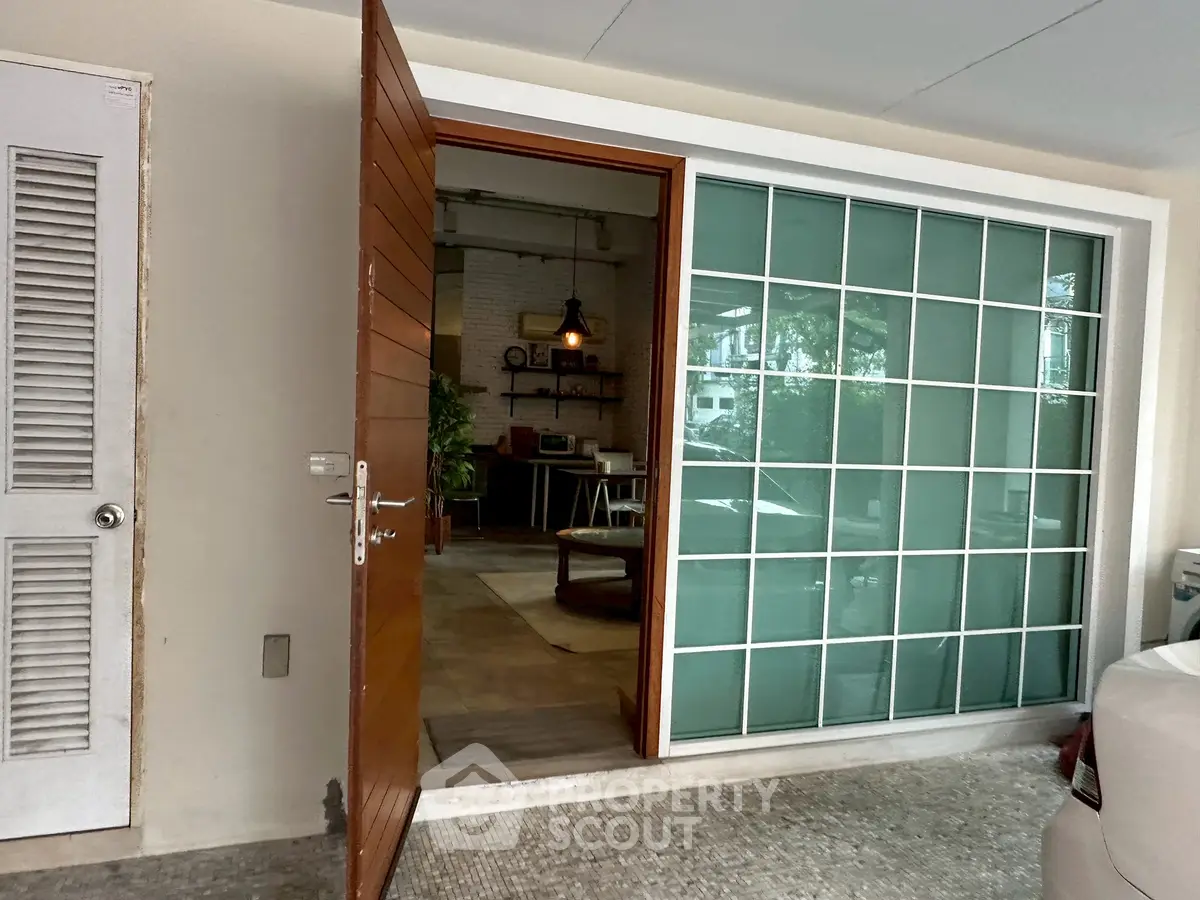 Chic modern entrance with glass panel door leading to stylish interior with cozy decor.