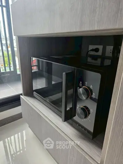 Modern kitchen with sleek microwave and balcony view, perfect for urban living.