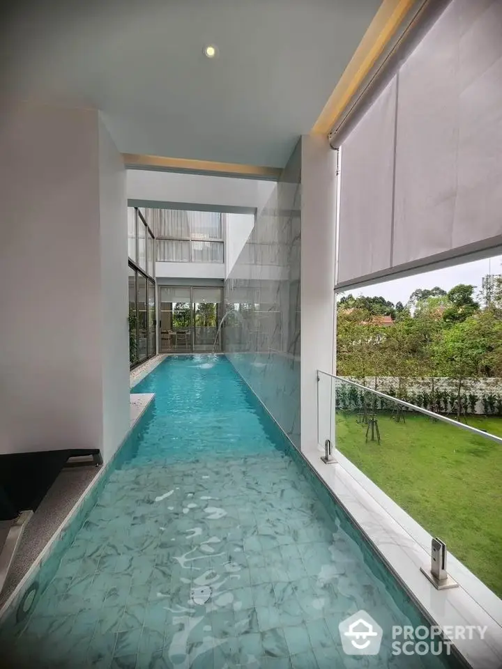 Luxurious indoor pool with glass walls overlooking lush garden