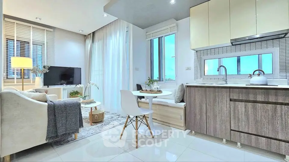 Modern open-layout living room with kitchen, featuring sleek furniture and large windows.