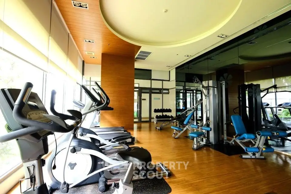 Spacious modern gym with state-of-the-art equipment and mirrored walls in luxury residential building.