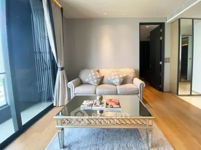 Elegant living room with plush sofa, mirrored coffee table, and floor-to-ceiling windows.