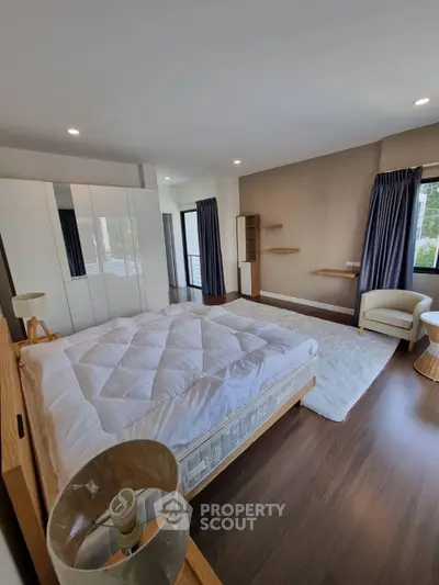 Spacious bedroom with modern decor and large windows for natural light.