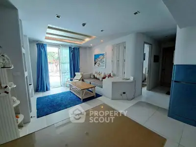 Modern living room with blue accents and natural light, featuring cozy seating and stylish decor.