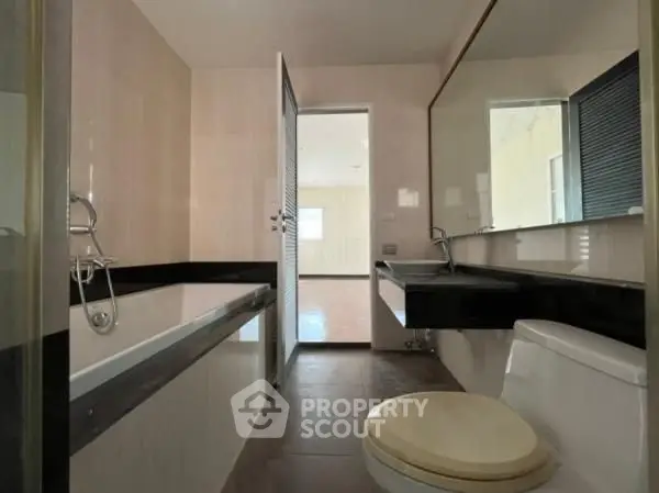Spacious bathroom with modern fixtures and large mirror in a contemporary home.