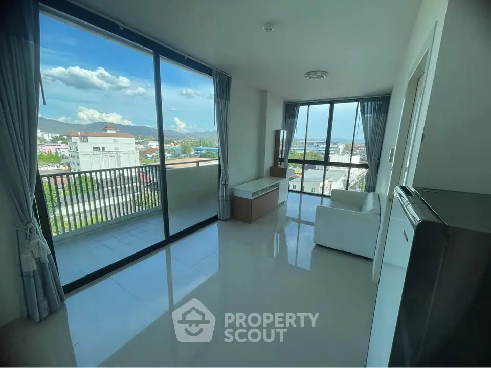 Bright living room with large windows and balcony offering stunning city views.
