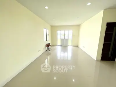 Spacious empty living room with glossy tile flooring and large windows for natural light.