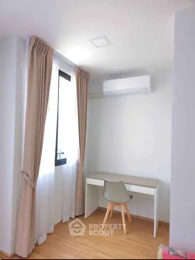 Bright study room with modern desk, chair, and large window with curtains, featuring air conditioning.
