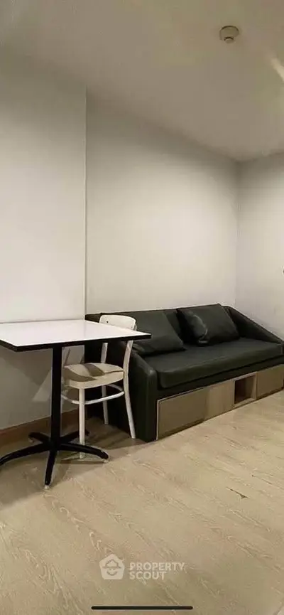 Modern minimalist living room with sleek black sofa and white table, perfect for urban living.