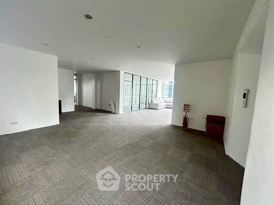Spacious modern living area with carpet flooring and large windows
