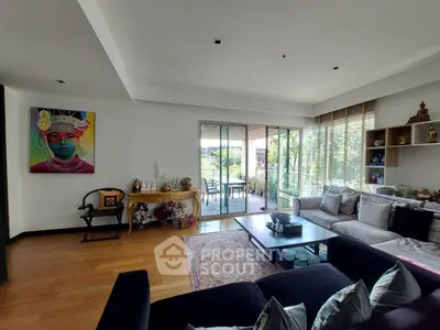 Spacious living room with modern decor and large windows leading to a balcony with garden view.