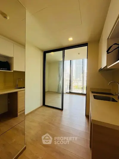 Modern kitchen with sleek design and open layout leading to a bright balcony with city views.