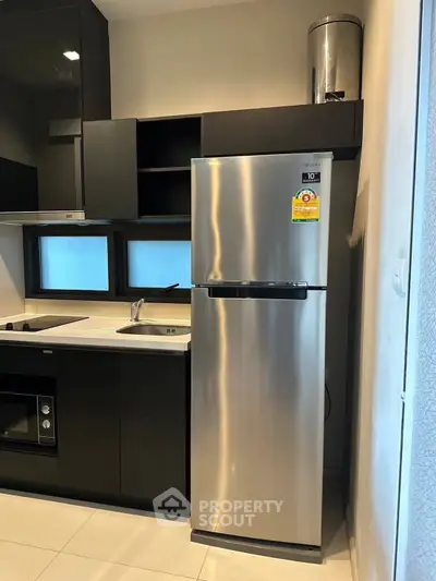 Modern kitchen with sleek black cabinets and stainless steel appliances.