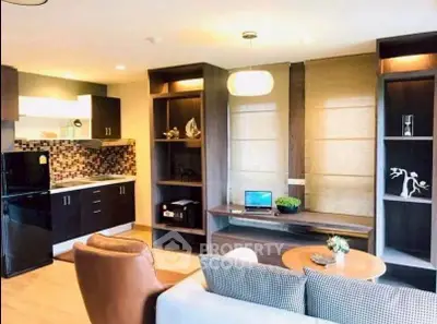 Modern living room with open kitchen, stylish shelving, and cozy seating area.