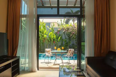 Luxurious living room seamlessly connects to a tranquil outdoor pool area with lush greenery, offering an oasis of relaxation and style.