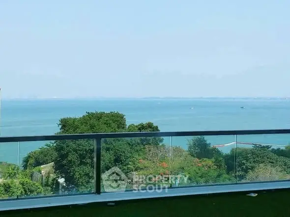 Stunning ocean view from a modern balcony with glass railing, perfect for relaxation.