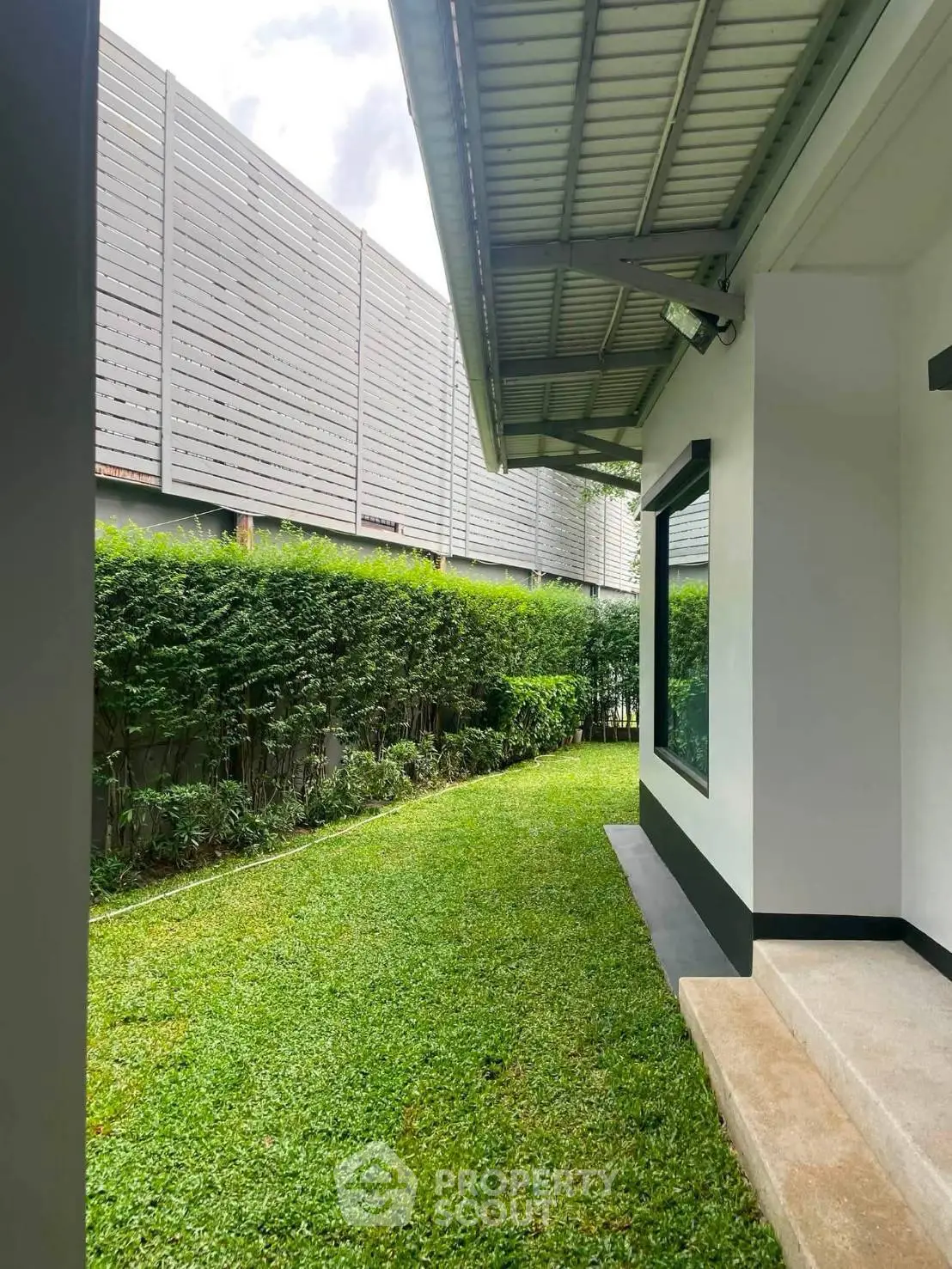 Charming garden view beside modern house with lush greenery and sleek architectural design.