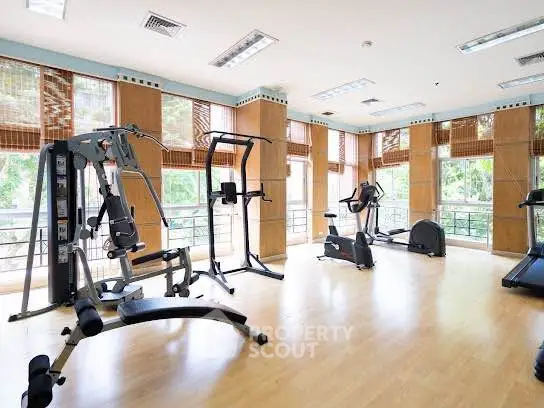 Spacious gym with modern fitness equipment and large windows offering a scenic view.