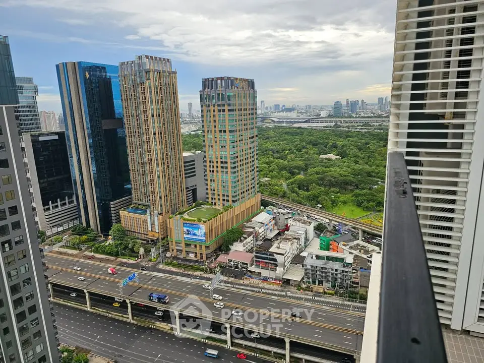 Stunning cityscape view from high-rise balcony overlooking lush park and modern skyscrapers.
