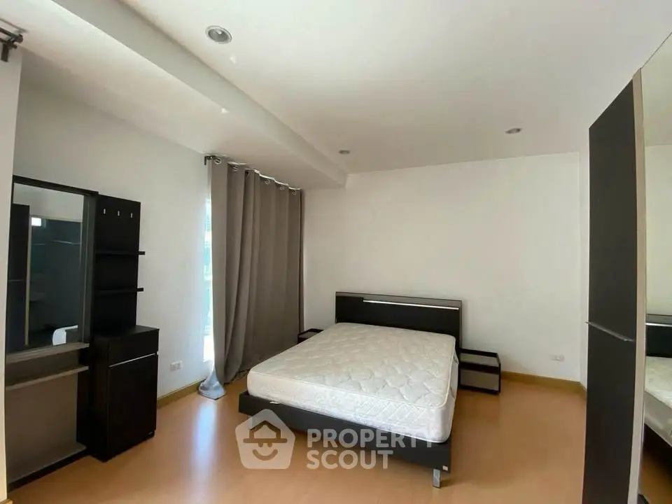 Spacious bedroom with modern furniture and natural light, perfect for comfortable living.