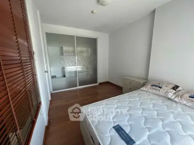 Spacious bedroom with wooden flooring and built-in closet in modern apartment.