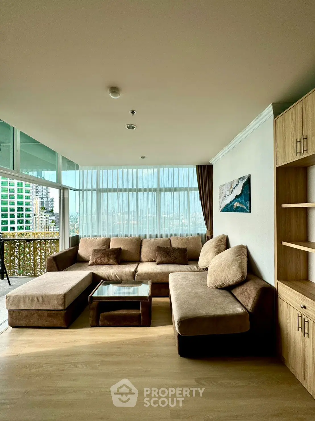 Spacious living room with modern sofa and city view balcony, perfect for relaxation.