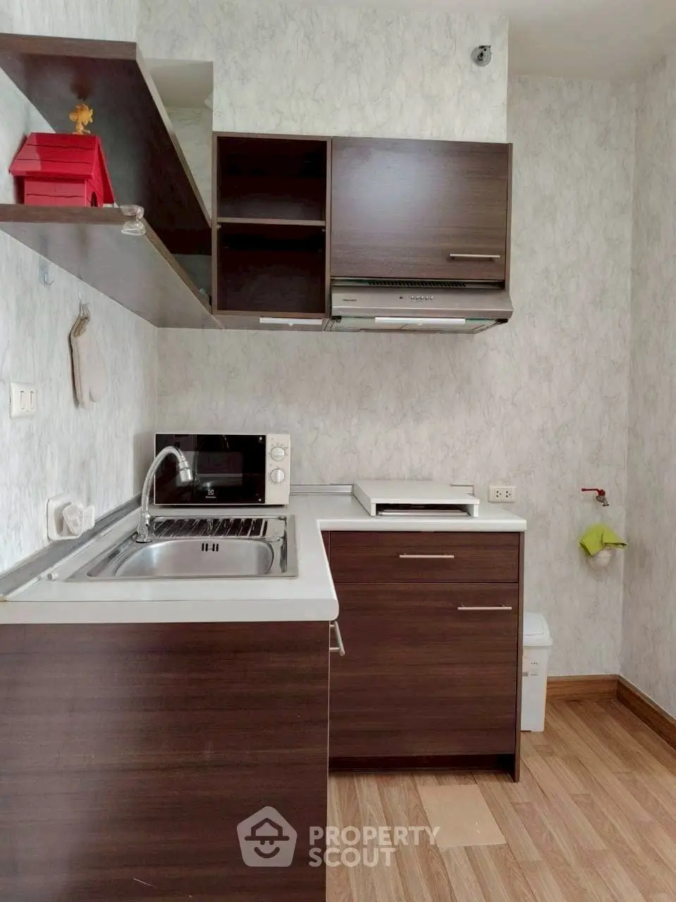Compact modern kitchen with dark wood cabinets and microwave, ideal for small spaces.
