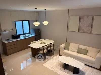 Modern open-layout kitchen and living room with stylish decor and natural lighting.