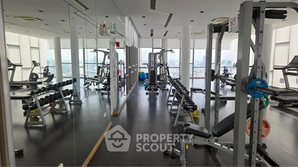Spacious modern gym with city view, featuring state-of-the-art fitness equipment and mirrored walls.
